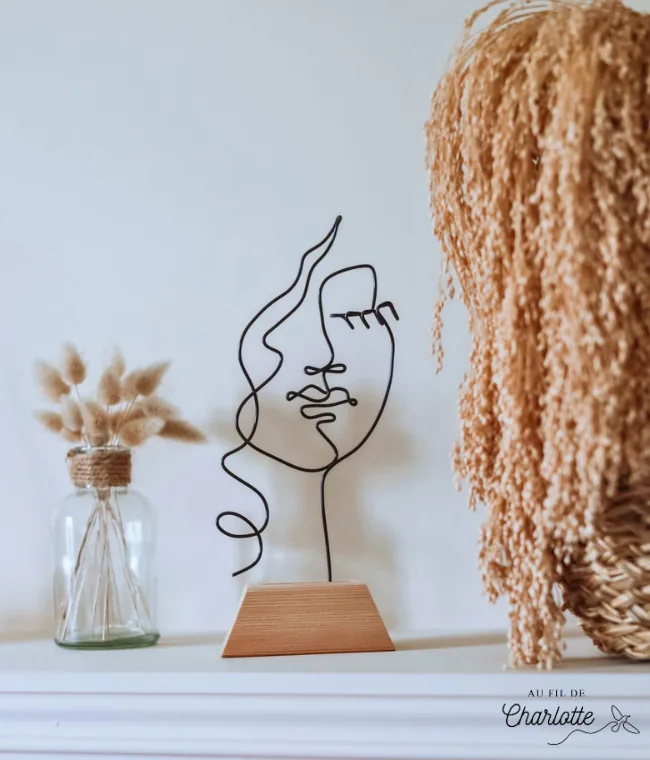 Visage de femme en fil de fer sur socle en bois