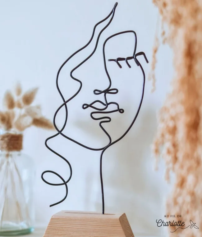 Visage de femme en fil de fer sur socle en bois