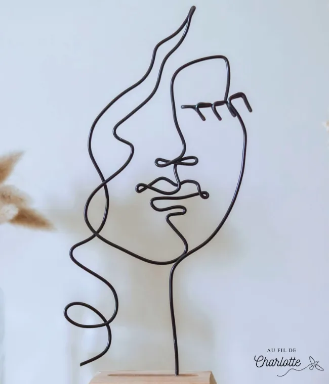 Visage de femme en fil de fer sur socle en bois