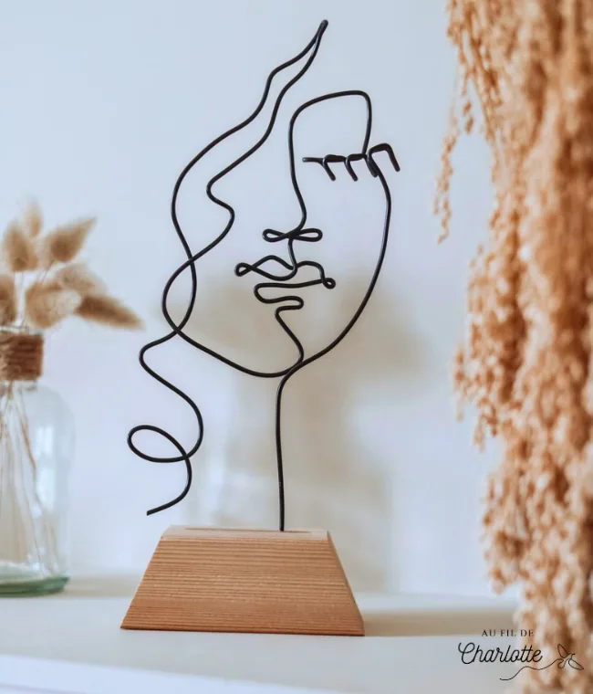 Visage de femme en fil de fer sur socle en bois