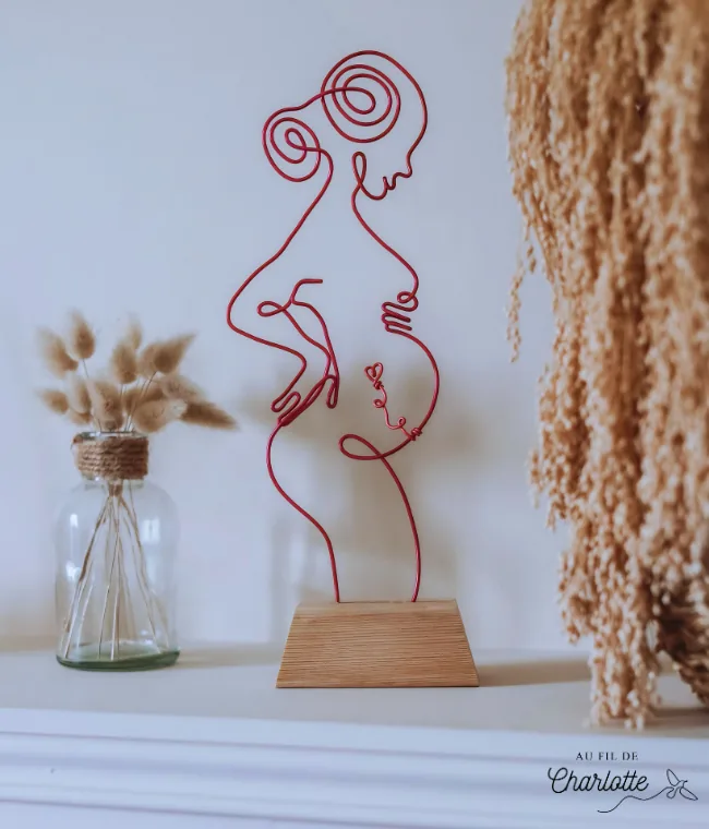 Femme enceinte en fil de fer sur socle en bois